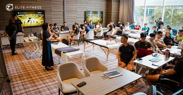 Không gian lớp học Road2Rehab × Elite Fitness tại Hà Nội với học viên theo dõi nội dung đào tạo và bàn thực hành bố trí phía trước.