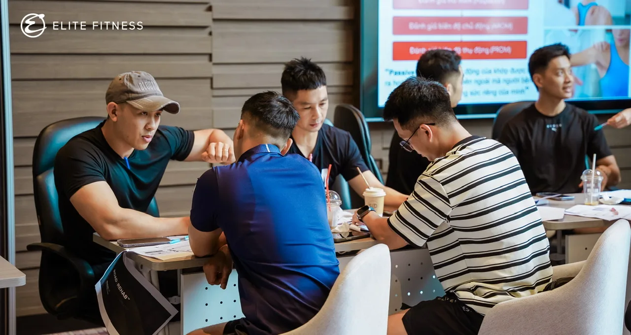 Huấn luyện viên Elite Fitness làm việc theo nhóm, ghi chép và trao đổi trong chương trình đào tạo Road2Rehab tại Hà Nội
